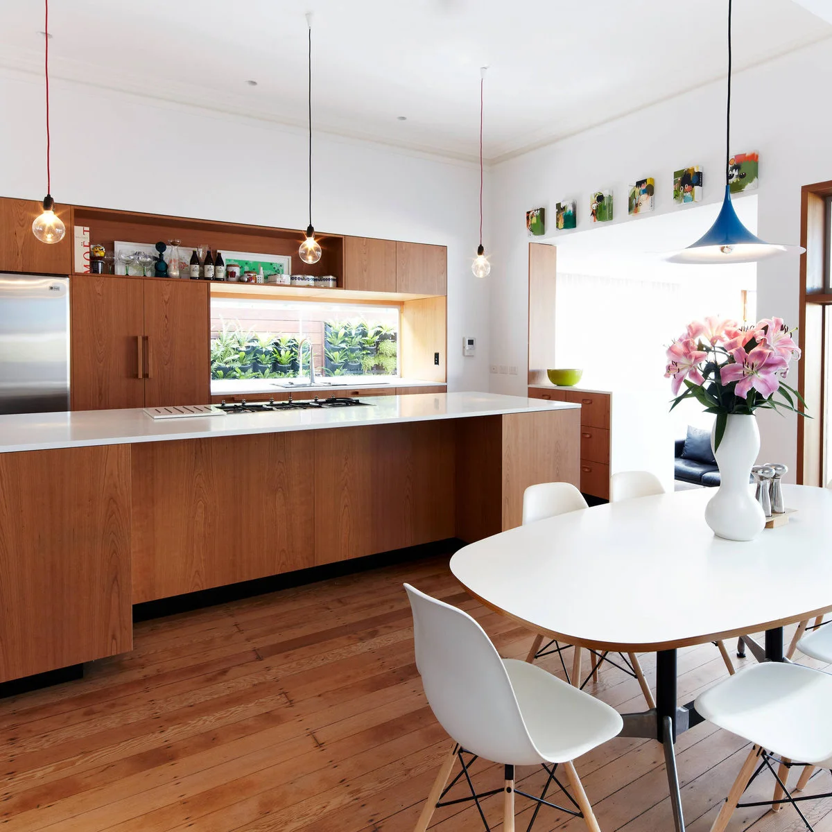Terrace-house kitchen with wood-colored cabinets, a narrow island and a white oval dining table