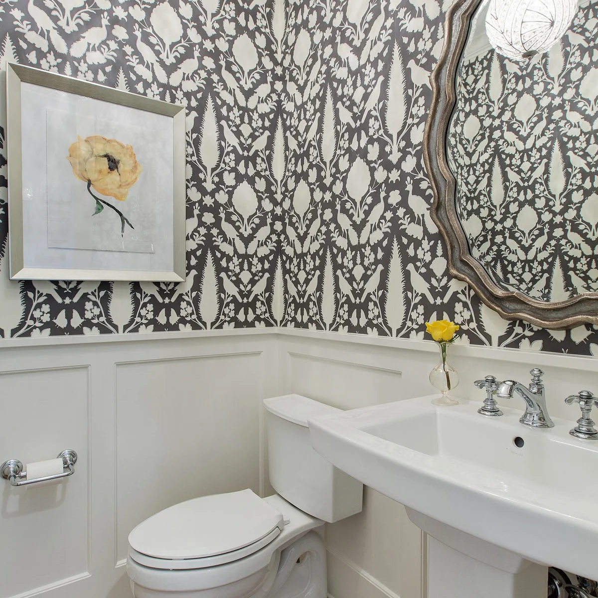 Yellow flower print on black-and-white wallpaper above white bathroom paneling