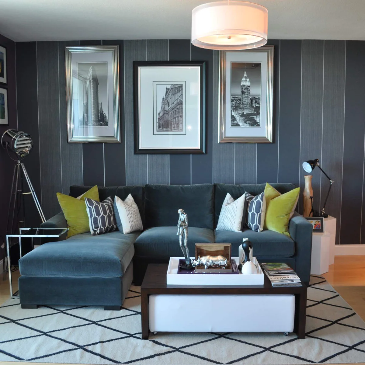 Blue-gray sectional with chartreuse cushions against a dark gray striped wall and a pale geometric rug.