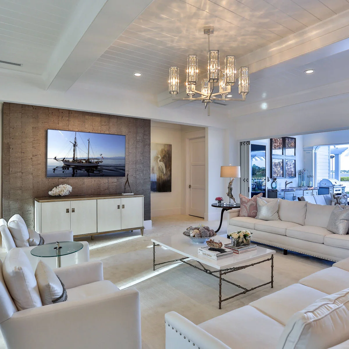 A white cabinet with gold-colored trim stands against a textured brown television wall with low flowers and a slender sculpture.