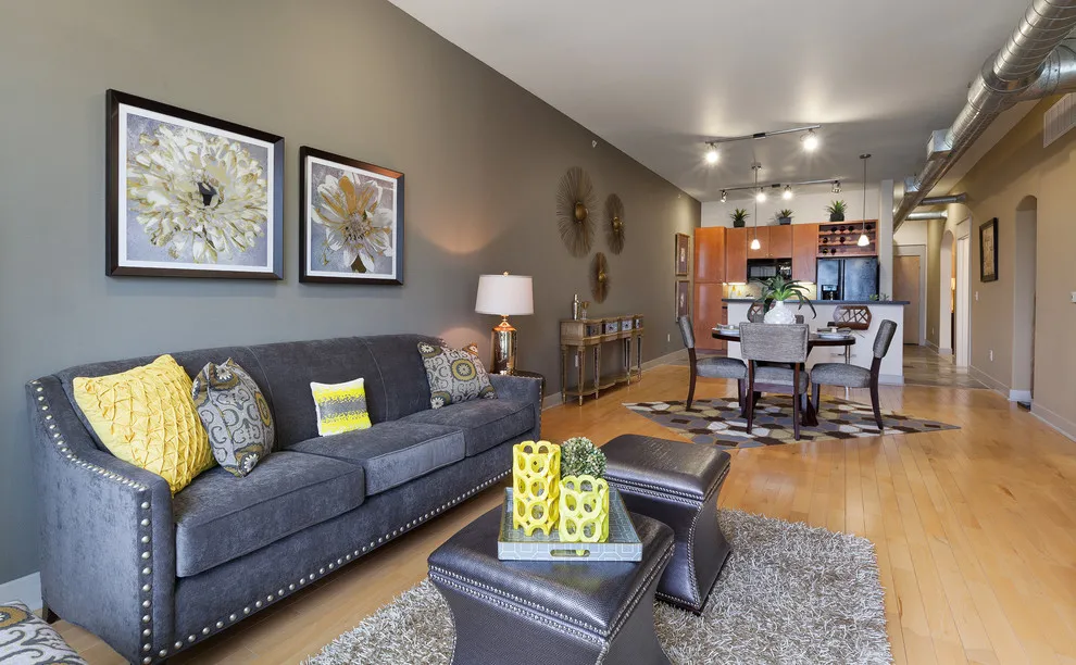 A dark gray sofa has yellow patterned cushions beneath botanical artwork