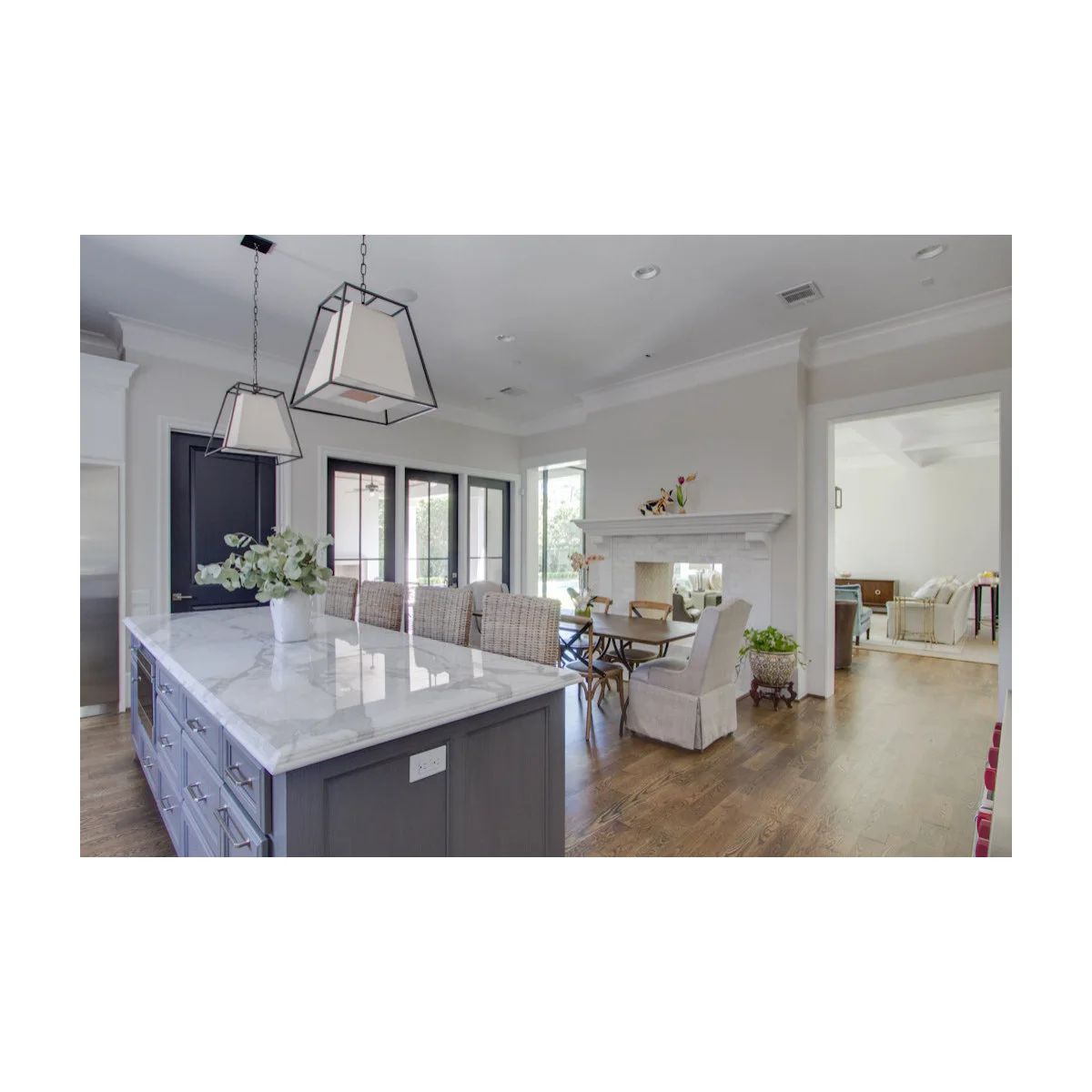 A pale fireplace wall separates a kitchen dining nook from a living room visible through a side opening.