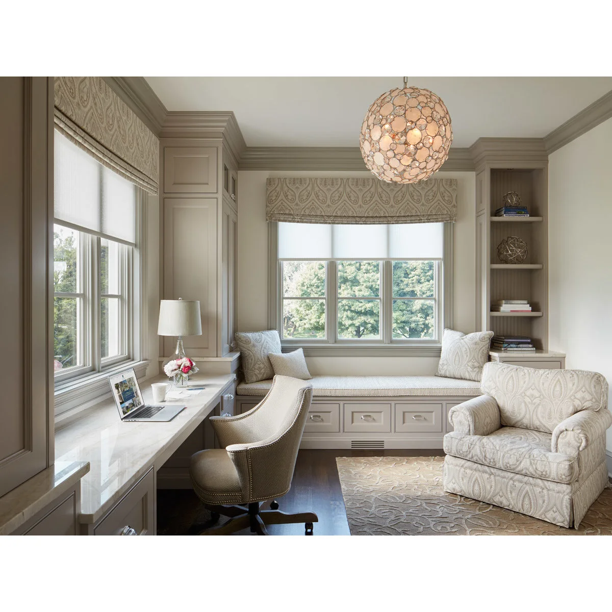 Pale home office with long window desk, upholstered desk chair, window bench and patterned armchair