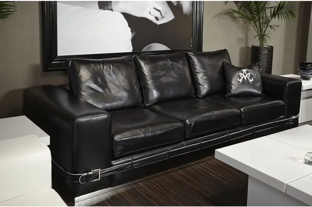 A black leather couch sits beneath a large black-and-white framed picture beside a pale low coffee table