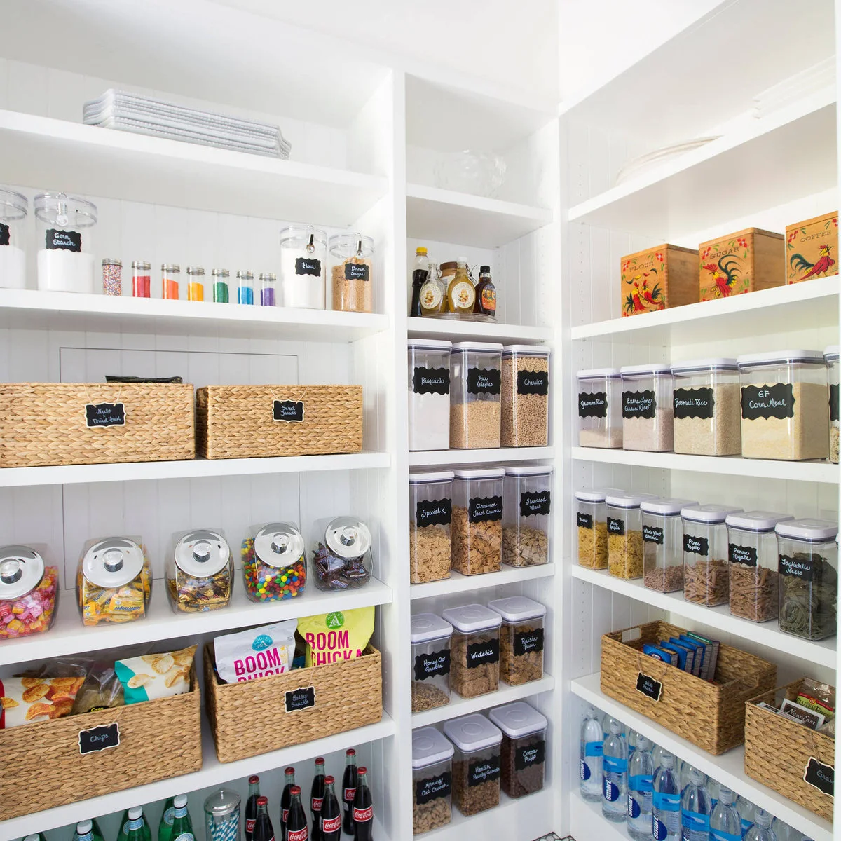 White pantry shelves with labeled rectangular containers and woven baskets
