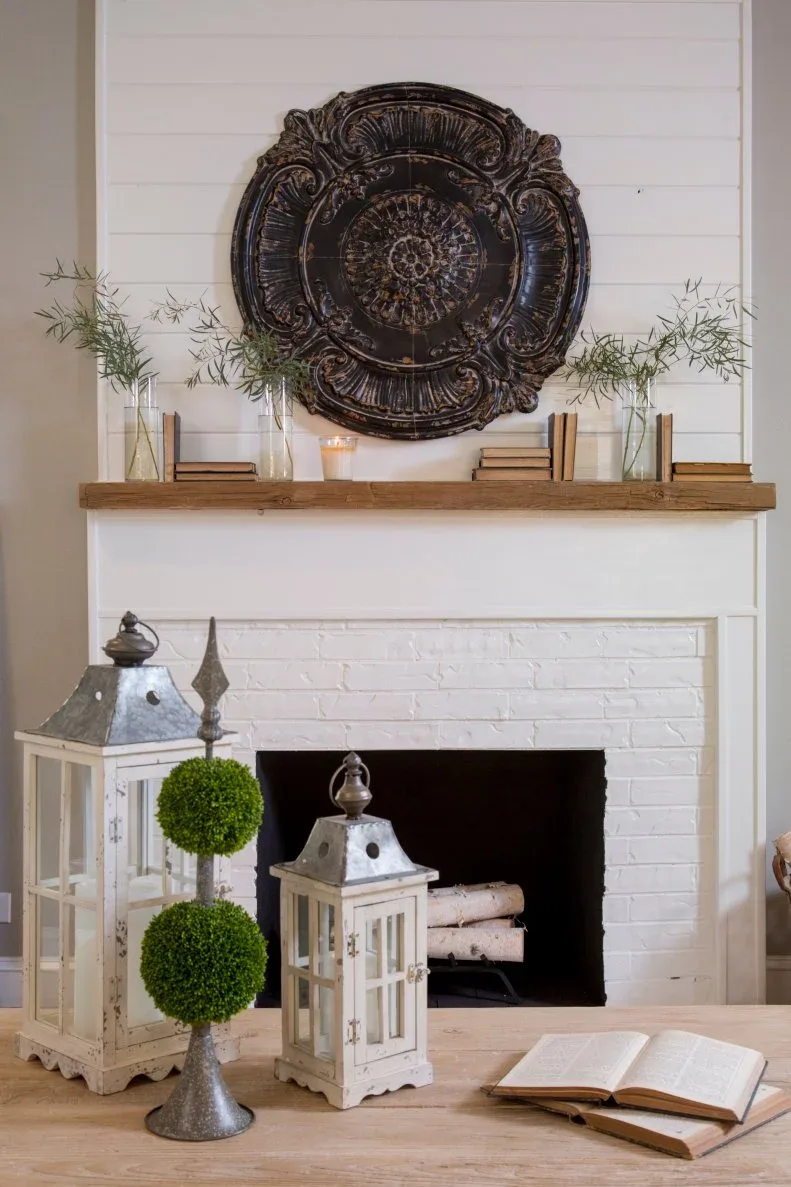 White brick fireplace with two pale lanterns, double-ball topiary and wood coffee table