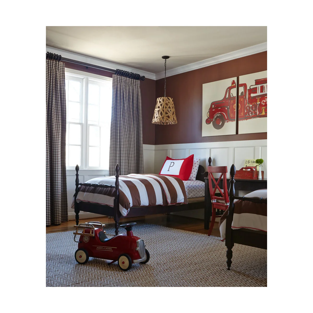 Two dark wood-colored beds with striped bedding, red accents and fire-engine artwork