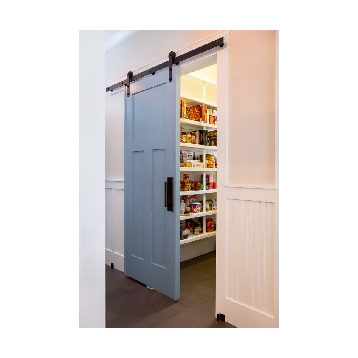 A blue-gray sliding panel on a black track partly covers white food shelves beside pale wall paneling.