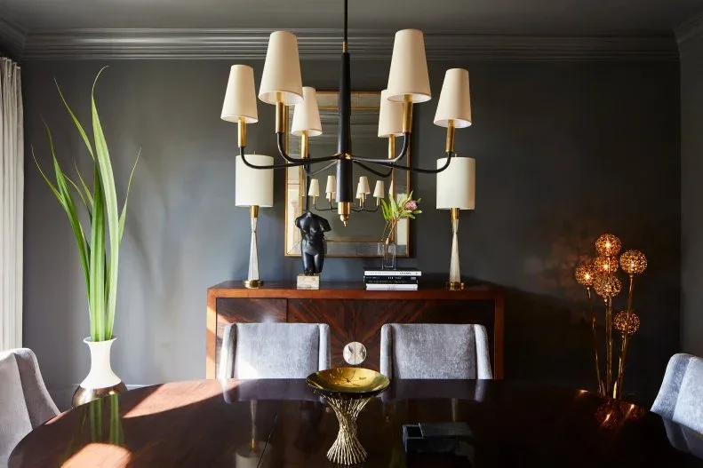 Dark wood sideboard with lighter angular borders beneath a rectangular mirror and two pale lamps