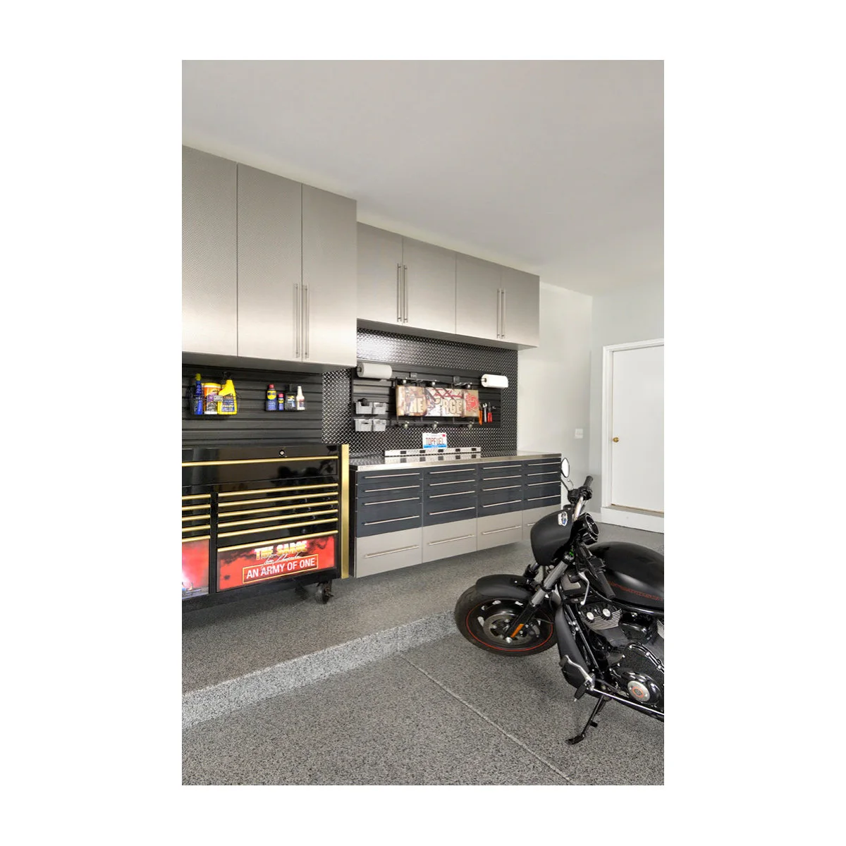 Motorcycle garage with silver upper cabinets, dark drawers, a rolling tool chest and a bench along the wall.