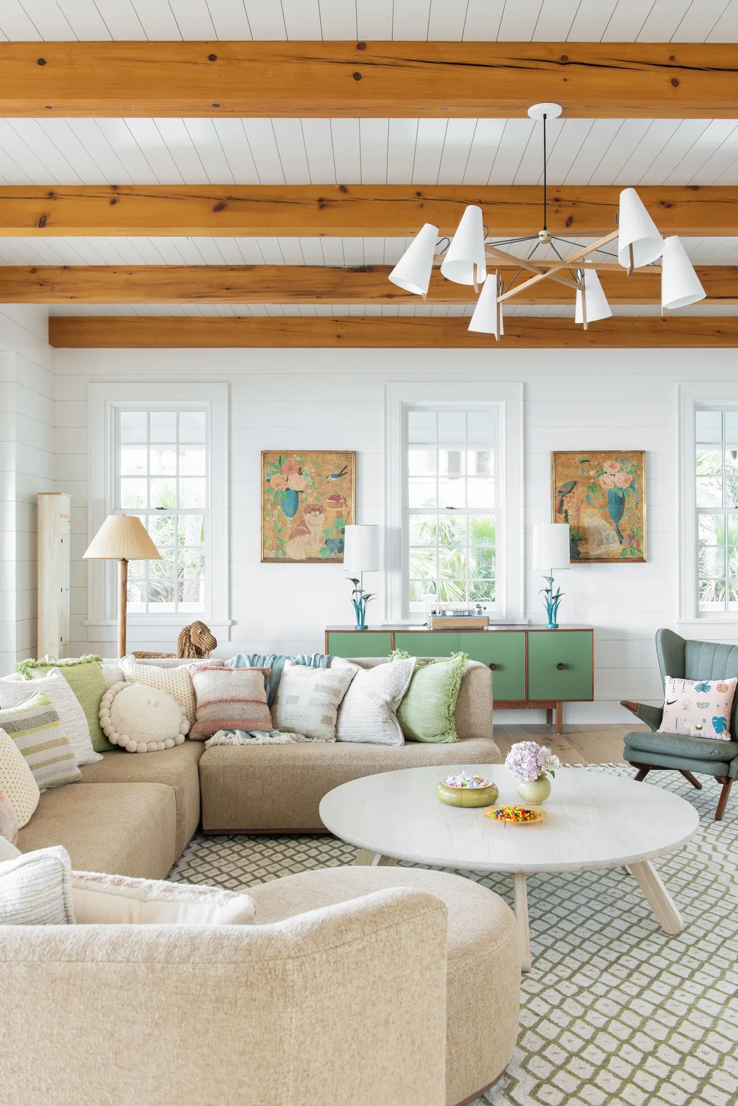 Pale round coffee table with small flowers and colorful bowls beside a neutral sectional