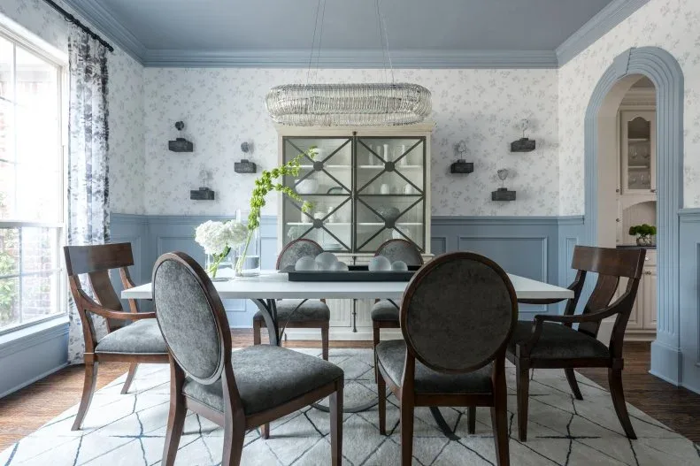 Blue lower-wall panels and blue arched doorway trim beneath pale patterned wallpaper in a dining room