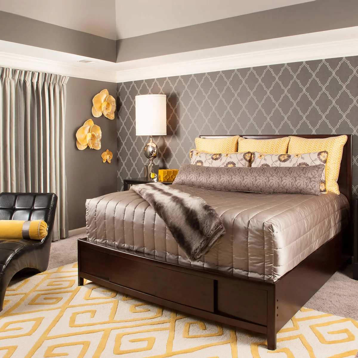 Gray bedroom with yellow pillows, pale patterned wall and a short textured throw