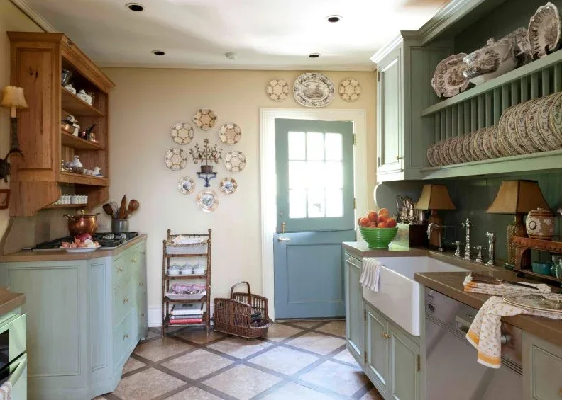 A green plate rack and pale green cabinets face timber cupboards in a kitchen with a blue divided door.