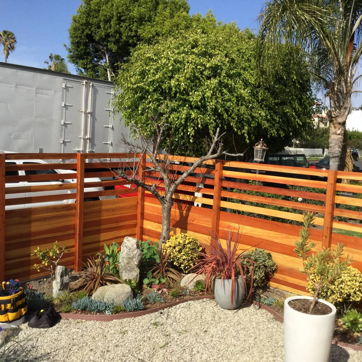 A warm wood front-yard fence with closely spaced lower boards and open horizontal rails above.