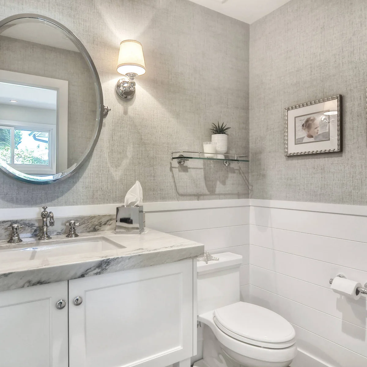 Compact white vanity with a reflective tissue box on the counter and a small plant on a glass shelf above.