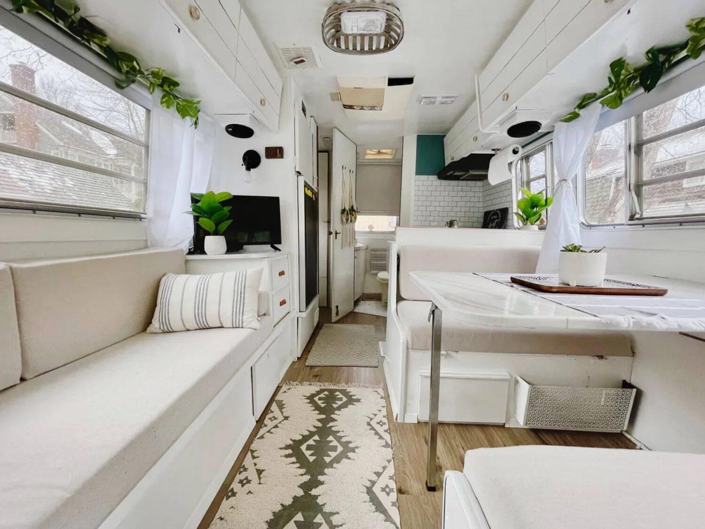 White camper lounge with a long cushioned bench and drawers opposite a compact dinette.
