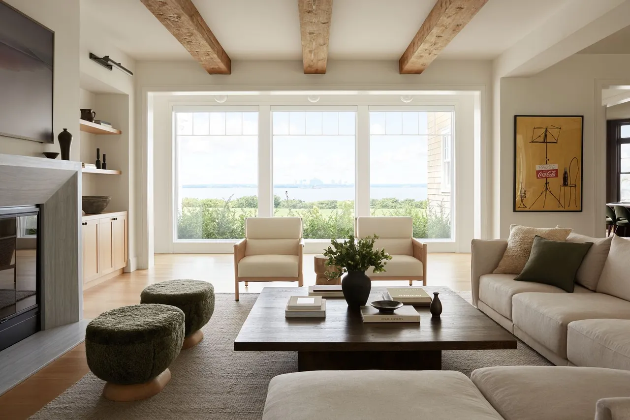 Pale seating sits beneath exposed timber beams beside a generous window.
