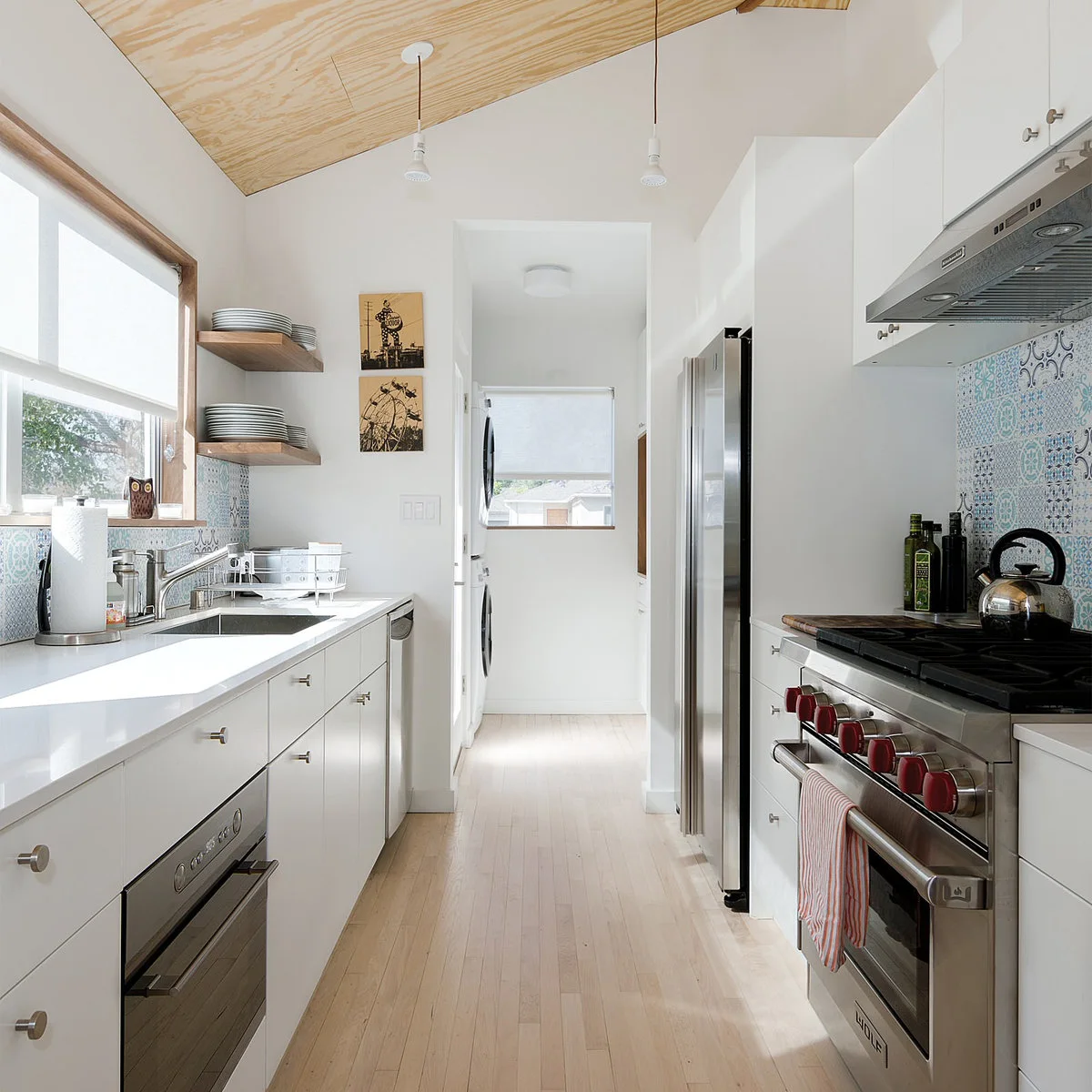 Pale wood sheet-panel ceiling over a narrow white kitchen with patterned backsplash