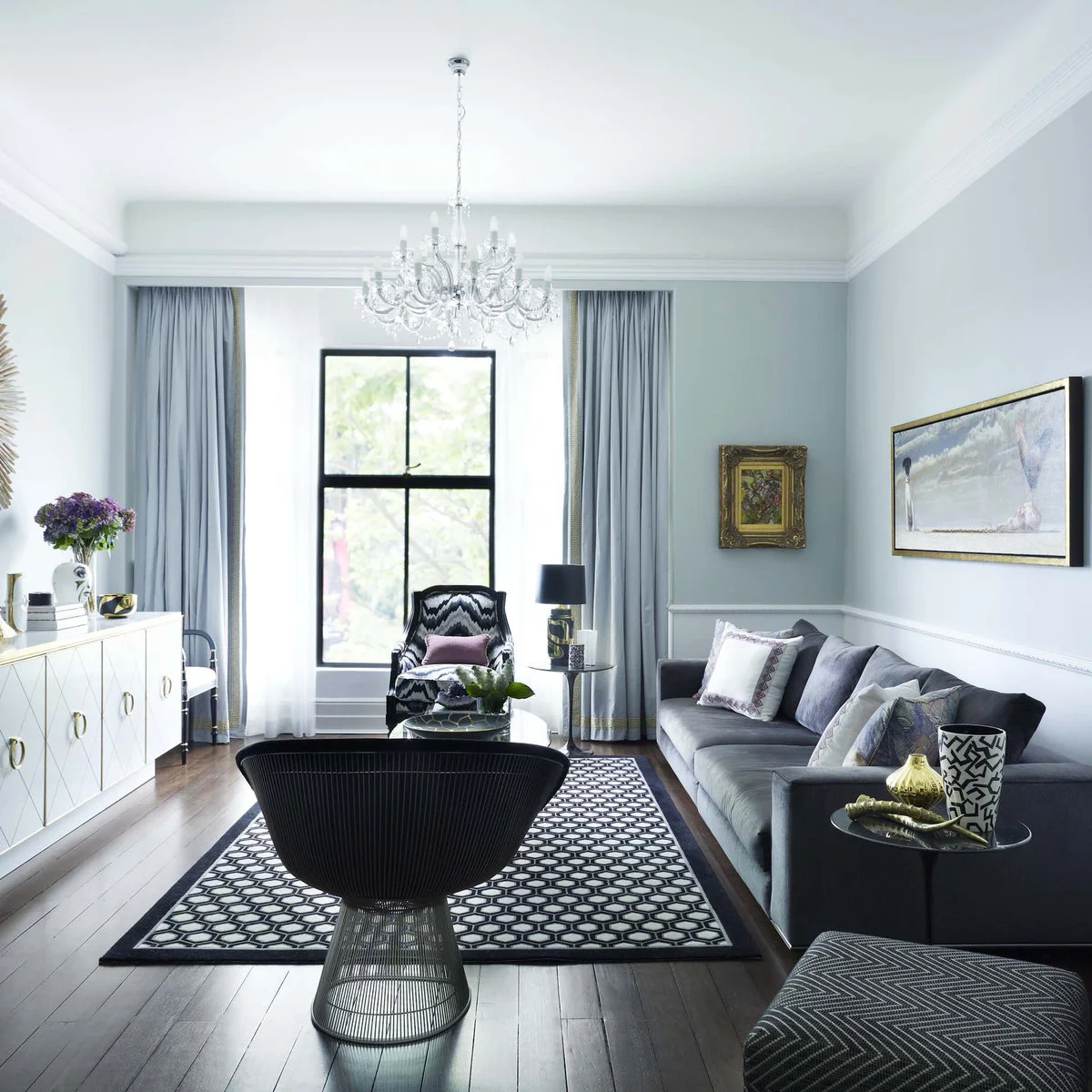 Narrow pale living room with dark patterned rug, black chair frame and gray sofa