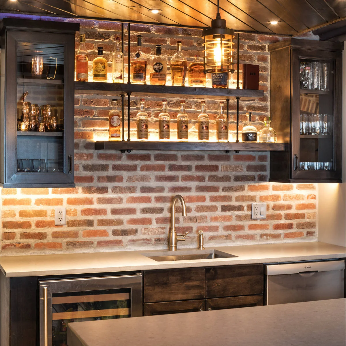 Basement wet bar with brick-patterned backsplash, open bottle shelves and glass-front cupboards
