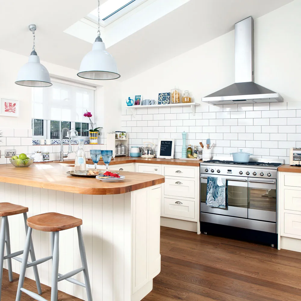 Pale cream cabinetry sits below white tile beside a timber breakfast counter
