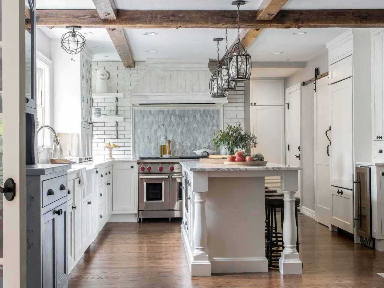 White subway tiles with dark joints surround a blue-gray patterned inset beneath a broad kitchen hood.