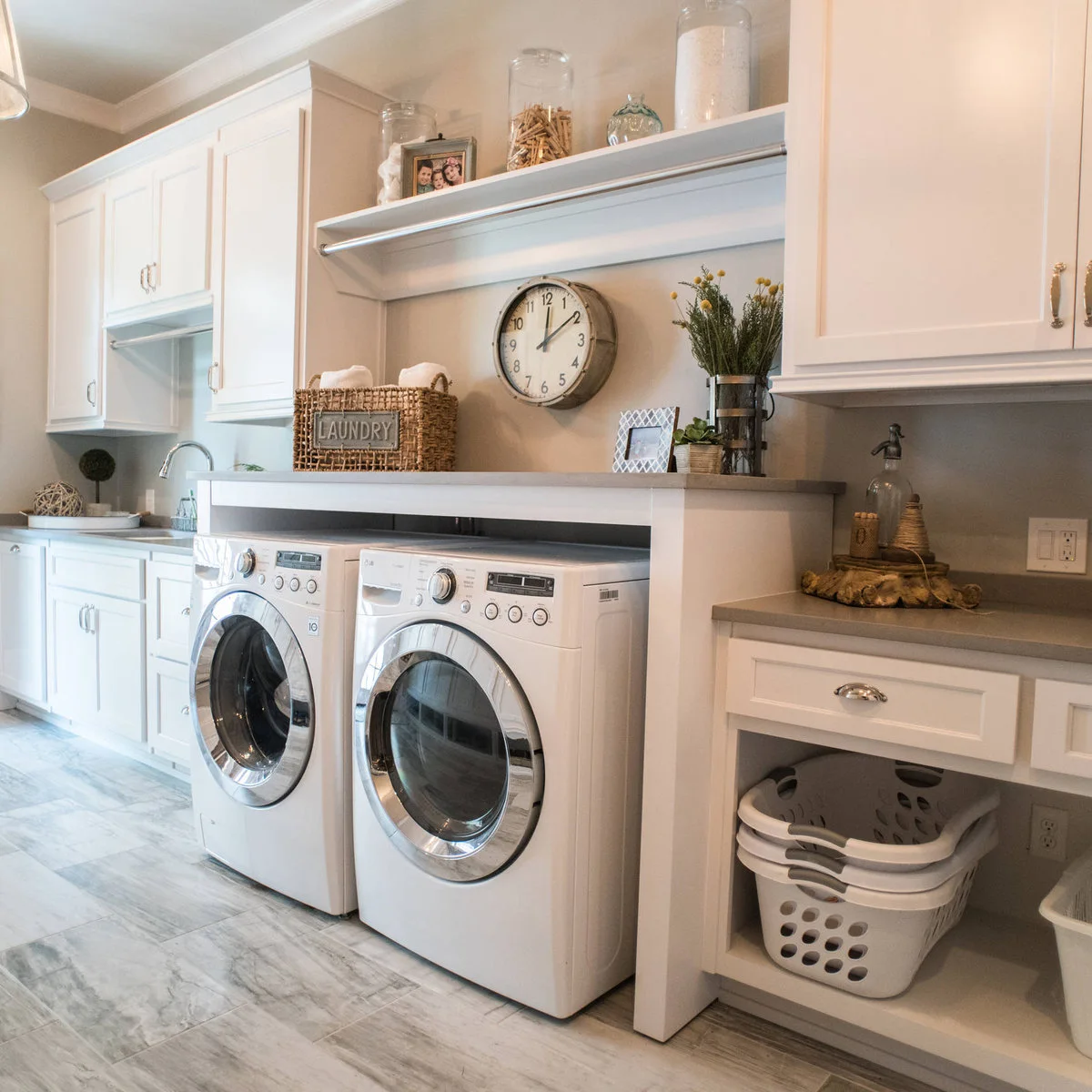 White laundry room with a raised counter over appliances and stacked empty baskets in a lower open bay to the right