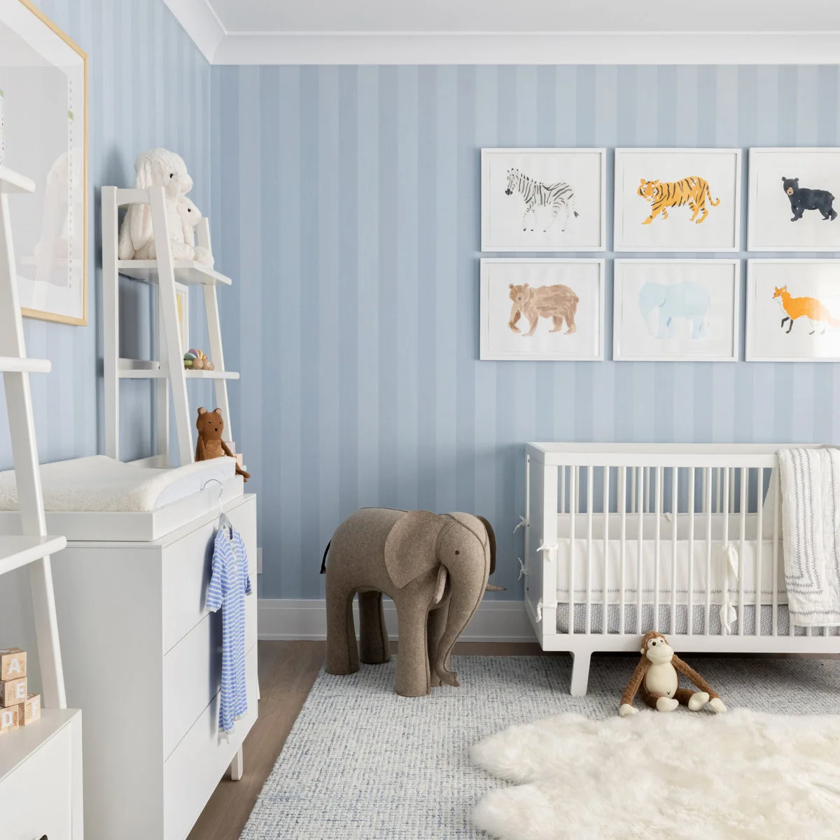 Pale blue striped nursery with six animal prints, white furniture and a large fabric elephant
