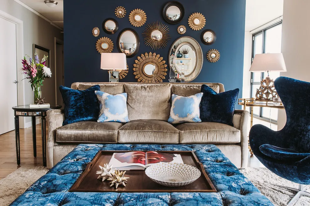 A navy wall displays a collection of decorative mirrors above a plain taupe sofa
