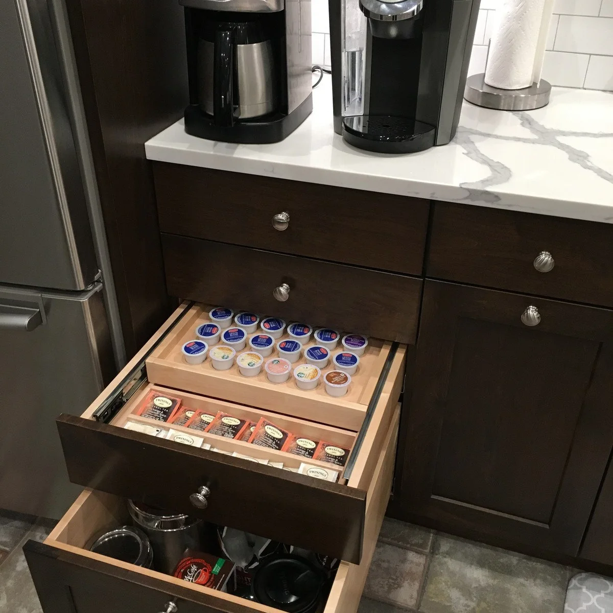 Coffee counter with an open two-level drawer storing pods above tea and spare equipment below