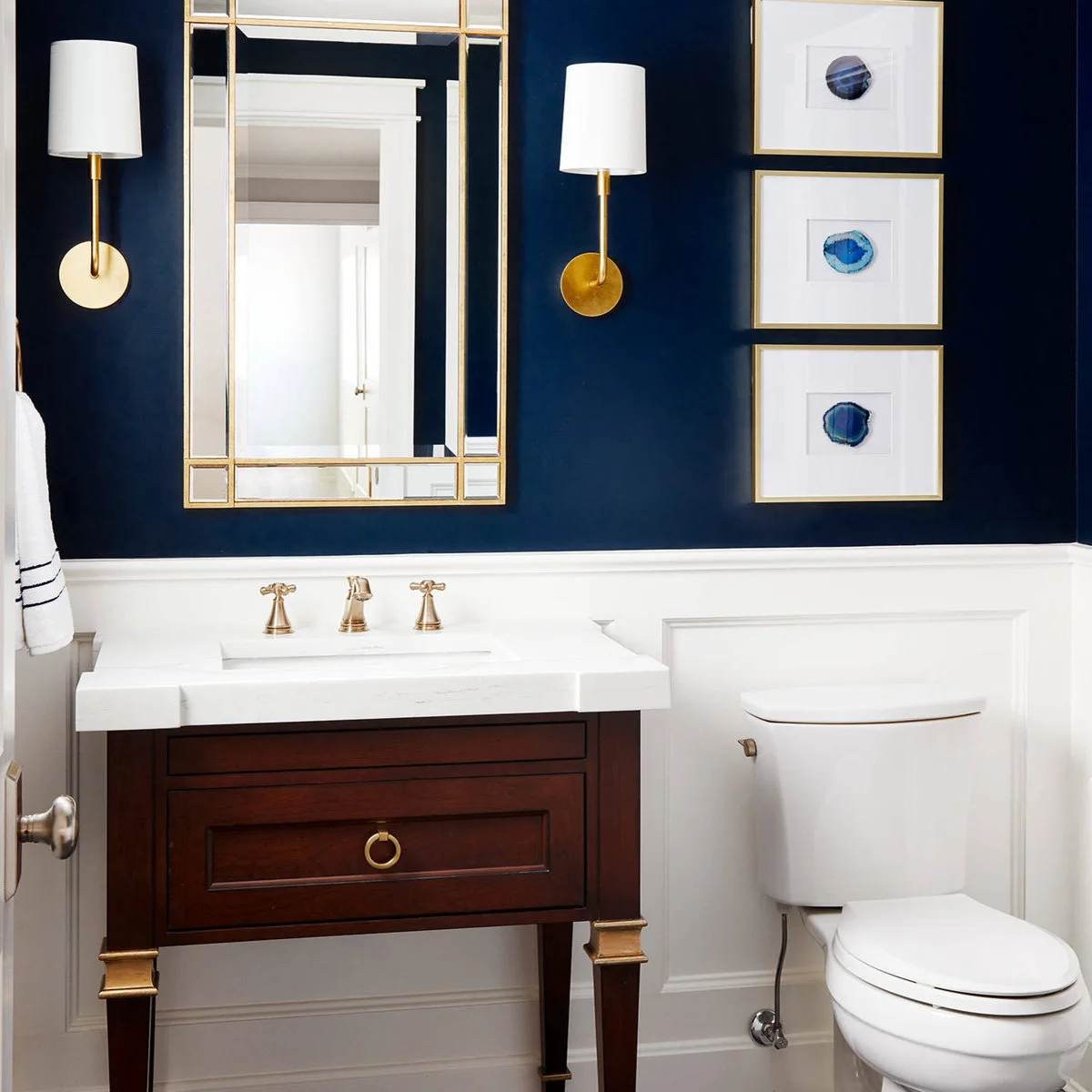 Three gold-framed blue circular prints stacked beside a navy bathroom mirror