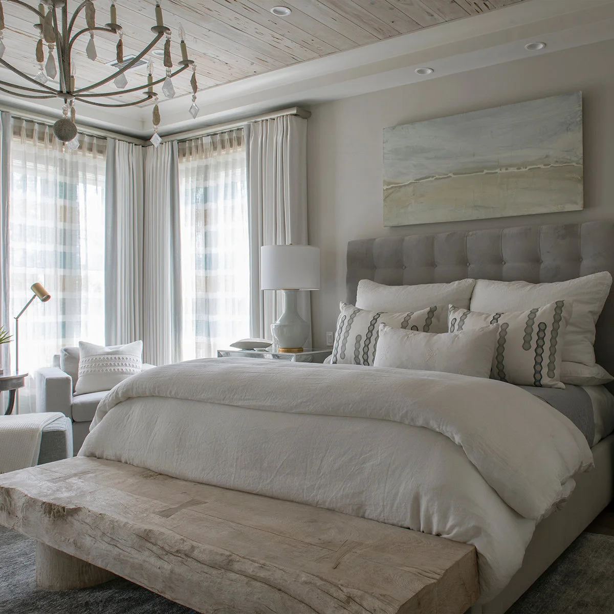 Thick pale wooden bench with rounded supports in front of a white upholstered bed
