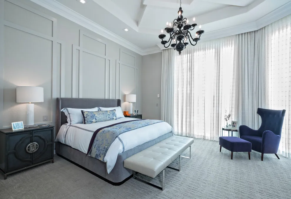 Pale panels sit behind a bed beside long curtains and tall windows