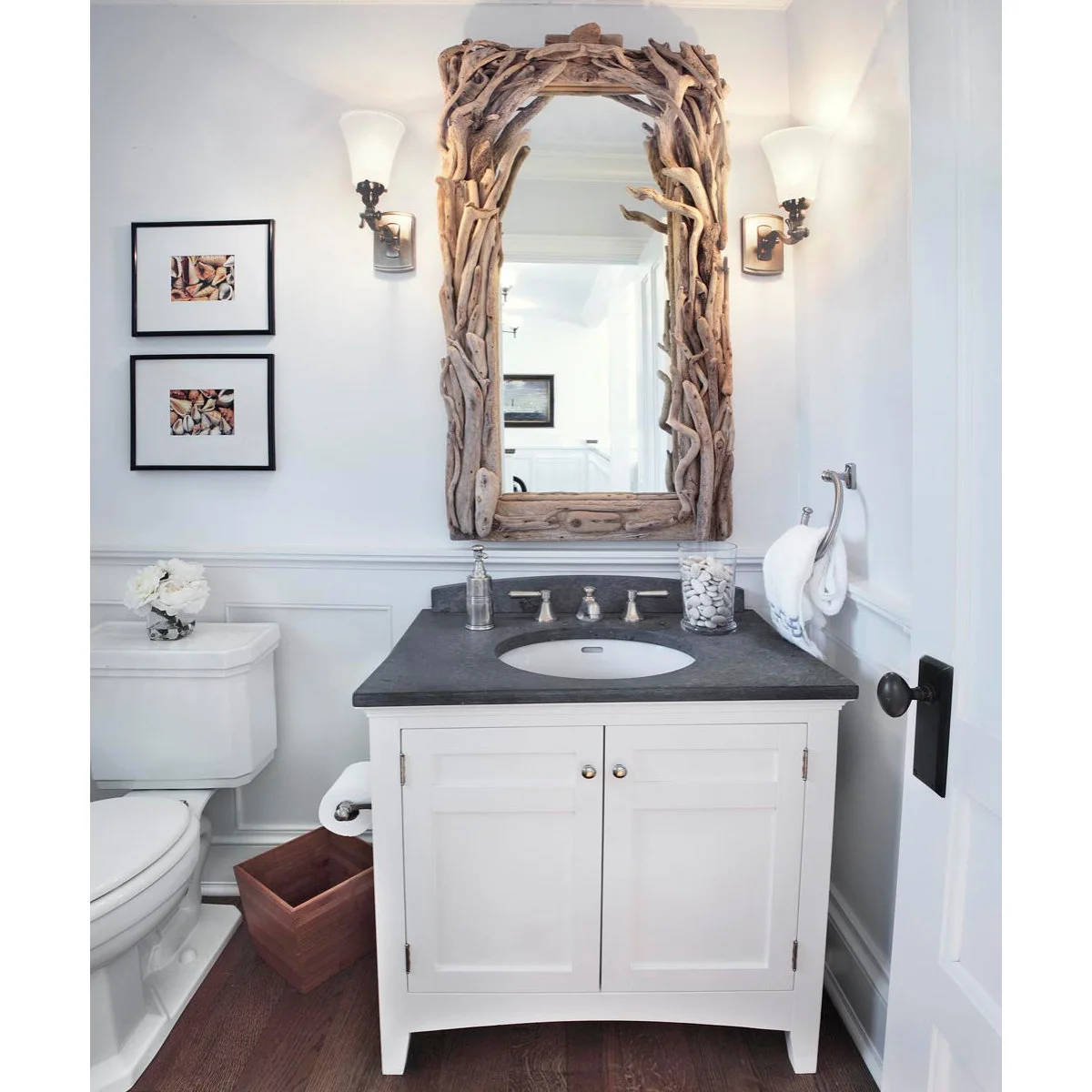 Two small shell pictures beside a large branch-framed bathroom mirror