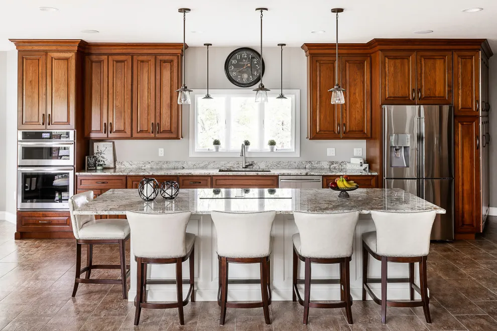 Warm wood cabinets surround a pale island with white upholstered stools
