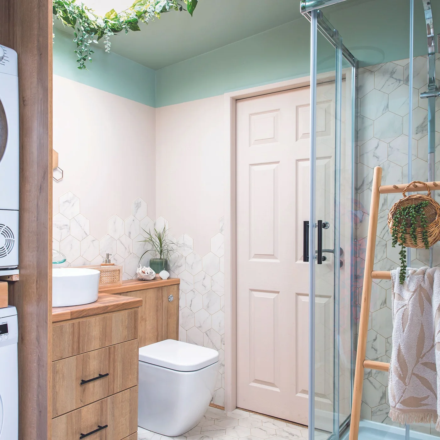 Pale bathroom with mint-colored ceiling and upper wall band above a wood vanity, white door and glass shower enclosure.
