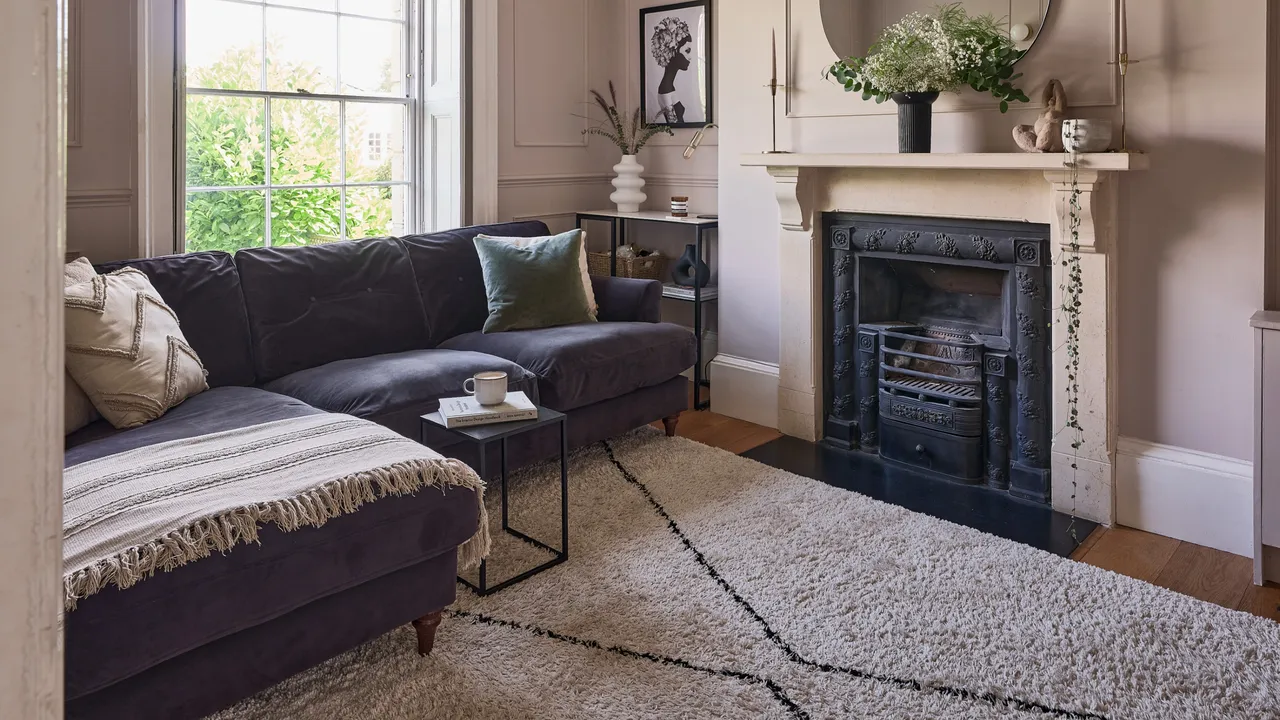 A dark sofa sits beside a fireplace and tall window in a compact living room