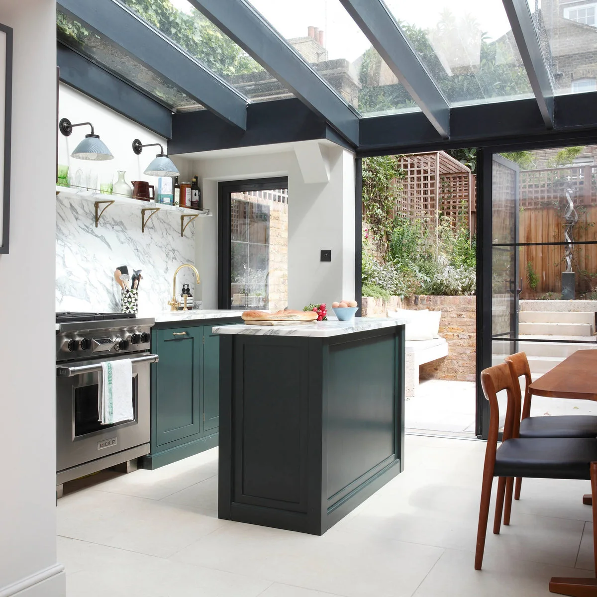 Green terraced-house kitchen with a small island, glazed roof and garden doors