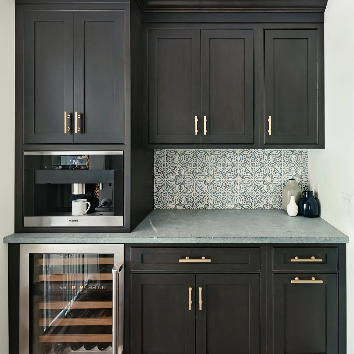 Dark fitted beverage cabinetry with built-in coffee machine, patterned backsplash and open counter