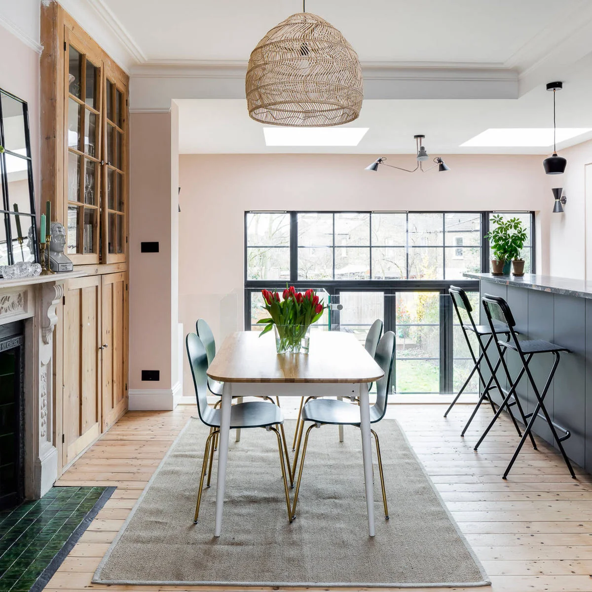 Terrace-house kitchen dining area with a small table, period fireplace and glass-front wood-colored cupboard