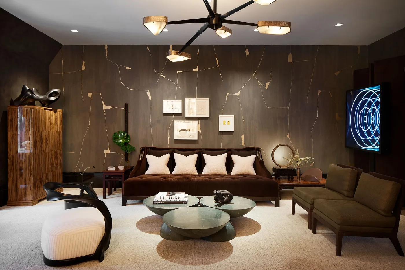 Dark brown patterned living room wall behind a brown sofa, pale cushions and rounded nesting tables