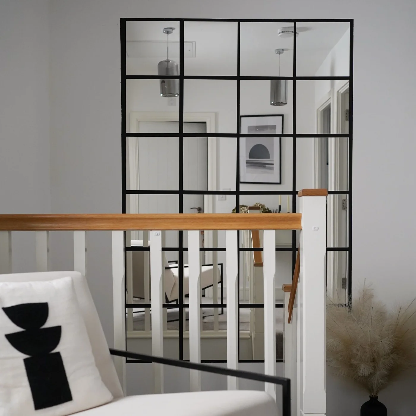 Tall grid of square mirrors with black spacing on a stair landing wall
