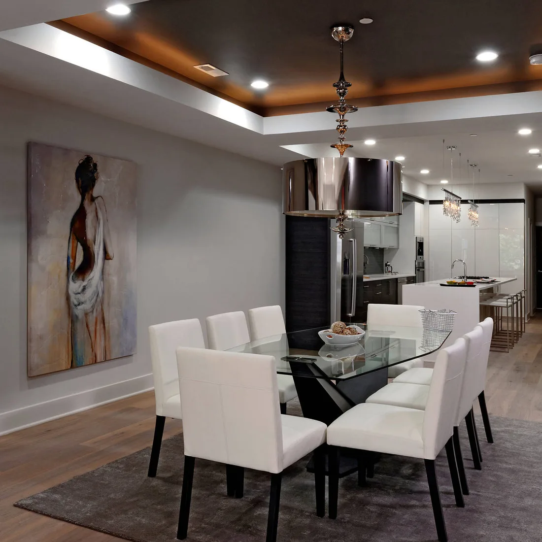 Muted gray-brown rug beneath a glass dining table and white chairs in an open kitchen setting