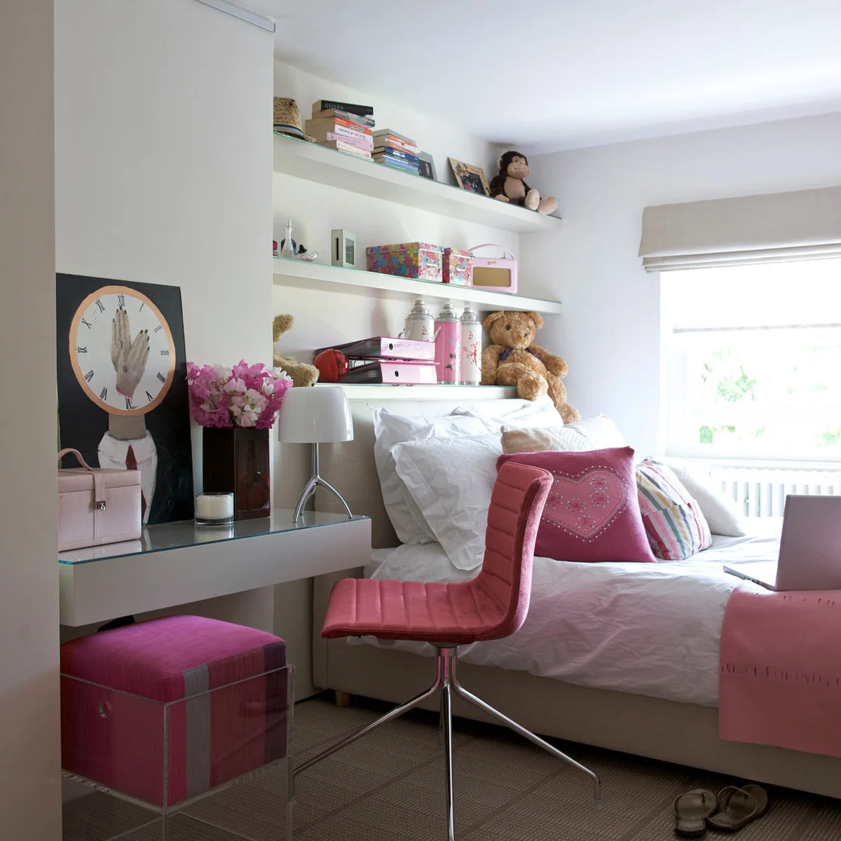 Small teen bedroom with pink desk seating, a white bed and long shelves for books and storage boxes