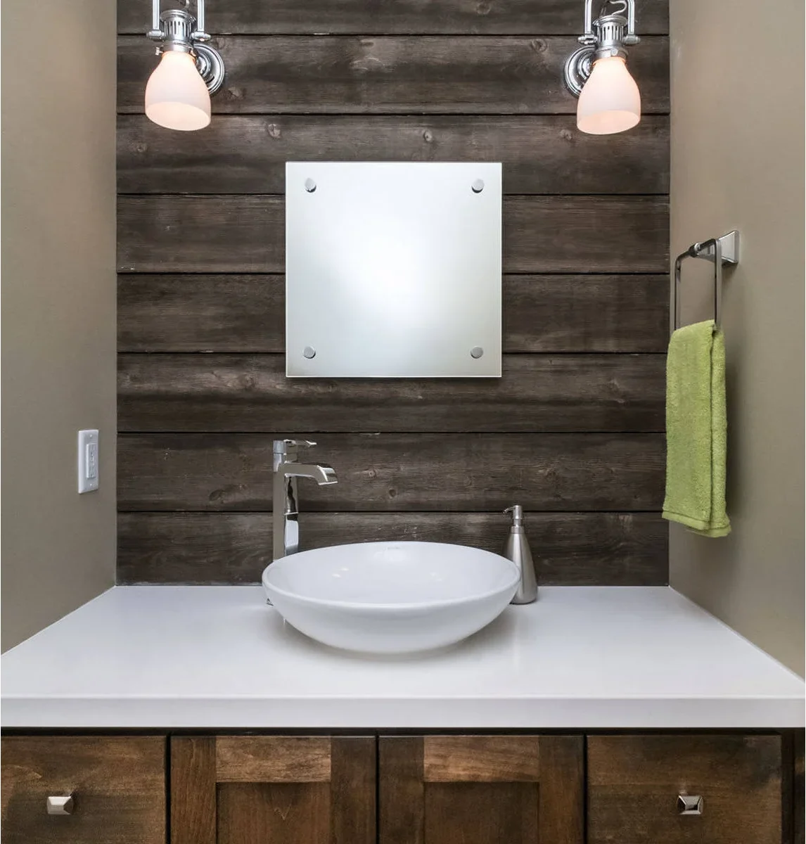 A round white vessel bowl sits on a broad white counter below a square mirror against dark horizontal wood boards.