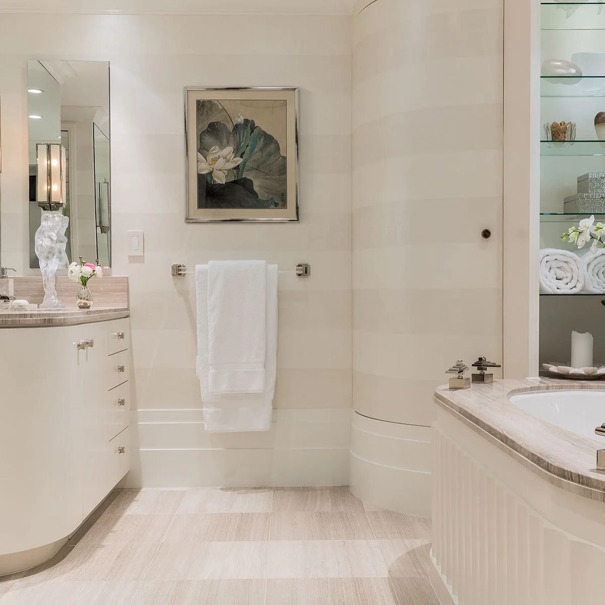 Framed leaf and flower artwork above white towels in a pale bathroom