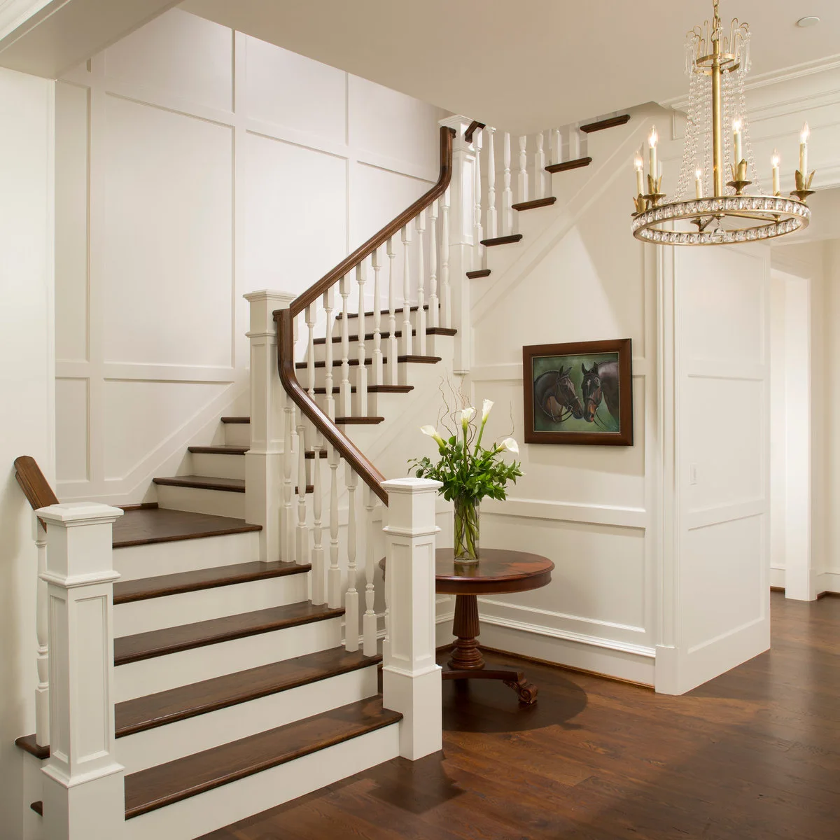 Tall white rectangular wall panels around a turning staircase with dark wood treads