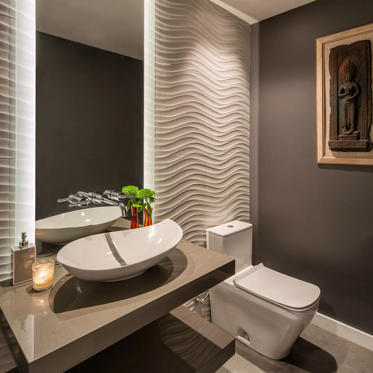 Framed dark relief on a brown powder-room wall beside white rippled tiles