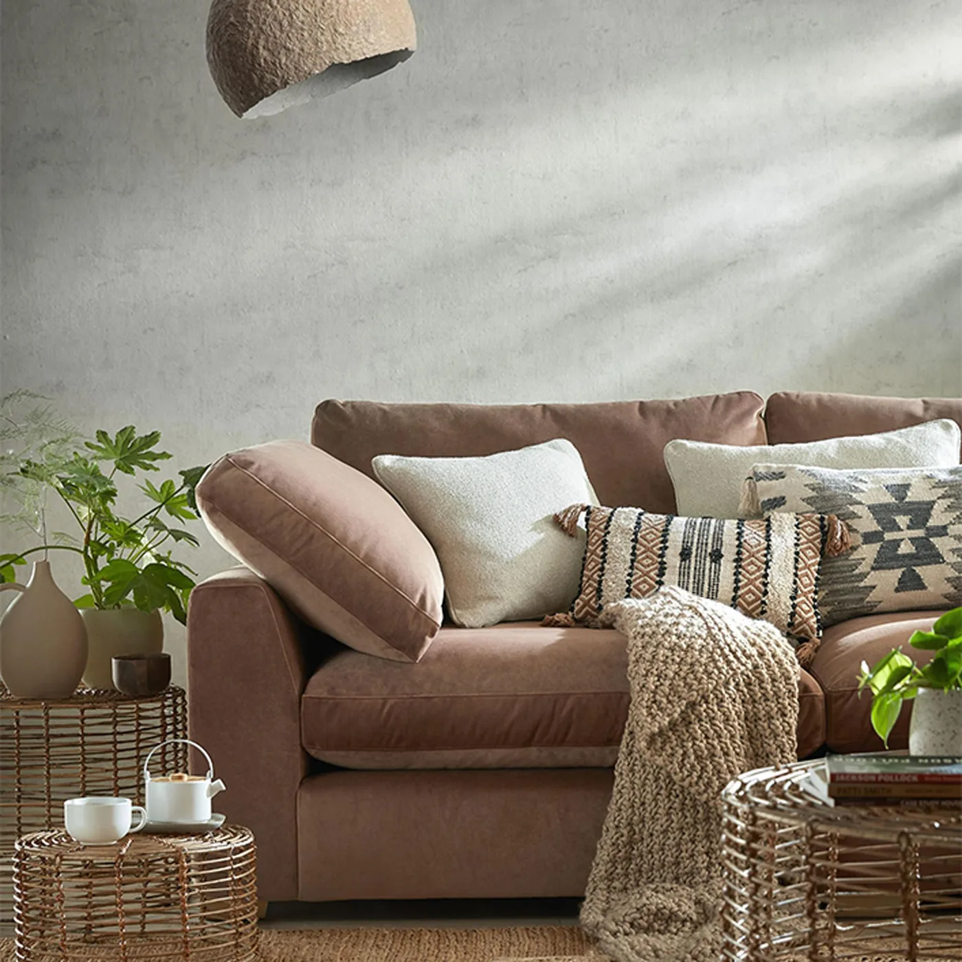 Brown couch with pale pillows, a smaller multicolored patterned pillow and a larger geometric cover.